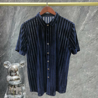 Chemise bleue à rayures en velours pendue à un cintre sur fond gris.