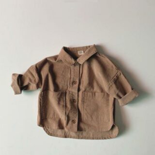 Sur fond gris clair, on voit une chemise marron pour bébé en velours côtelé.