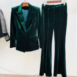 Ensemble de costume vert sapin sur deux cintres contre un mur blanc