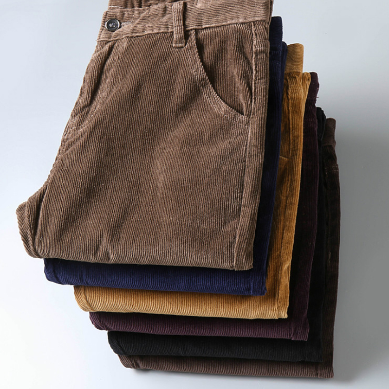 Pile de pantalons pliés en velours côtelé pour homme sur fond blanc.