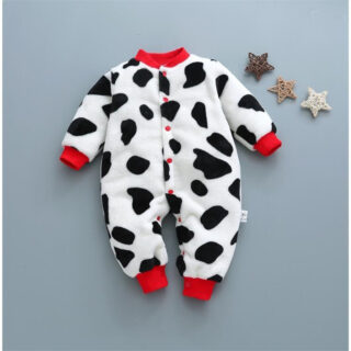 On voit un pyjama en velours pour bébé imprimé de taches de vaches, avec les encolures rouges.