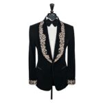 Photo d'une veste blazer ne velours noir avec des broderies dorées sur le col, sur un mannequin stockman porté avec une chemise blanche et un noeud papillon
