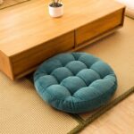 Photo d'un pouf de sol rond en velours côtelé bleu à côté d'une table basse en bois design
