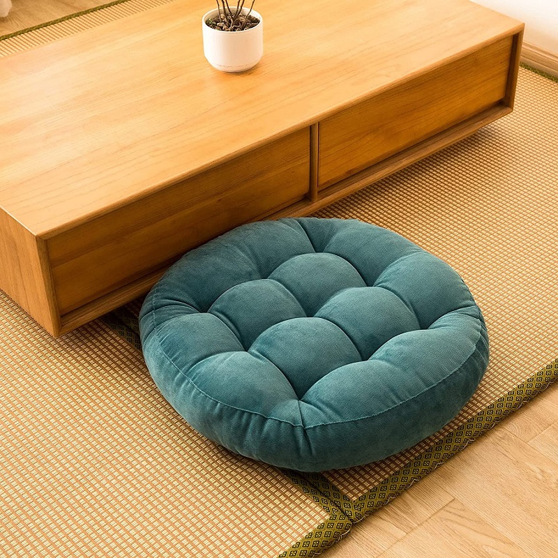Photo d'un pouf de sol rond en velours côtelé bleu à côté d'une table basse en bois design