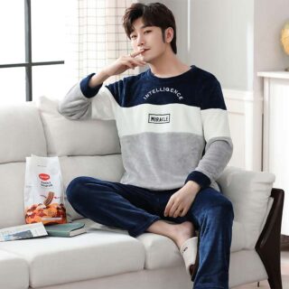 Homme assis dans un canapé avec un sachet de biscuit portant un pyjama en velours gris blanc et bleu
