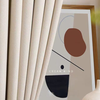 On voit un rideau en velours beige à chevrons, juste devant un cadre beige abstrait.