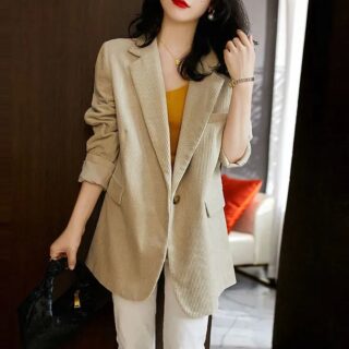 On voit une jeune femme qui porte une veste de costume oversize en velours beige côtelé.